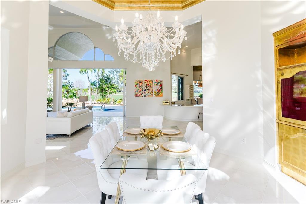 Dining area featuring light tile patterned flooring, ornamental molding, a towering ceiling, and an inviting chandelier
