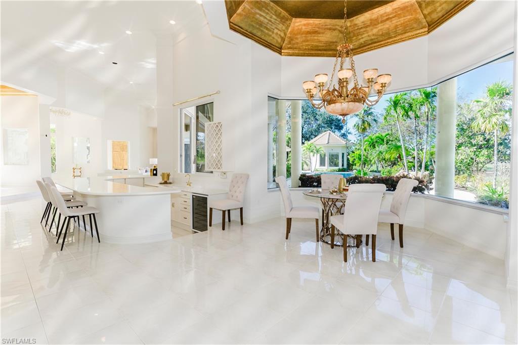 Dining space with a notable chandelier, beverage cooler, and a high ceiling