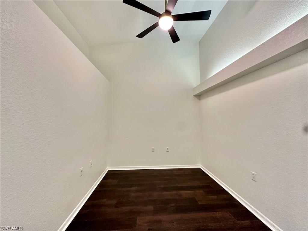 Spacious room with wood-finish flooring, high vaulted ceilings, and a contemporary ceiling fan