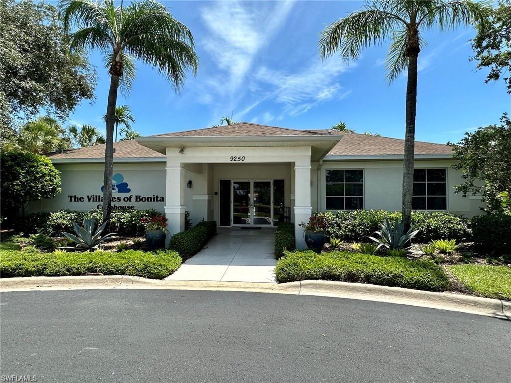 Clubhouse entrance featuring a portico, double entry doors, large windows, established landscaping, and a paved approach