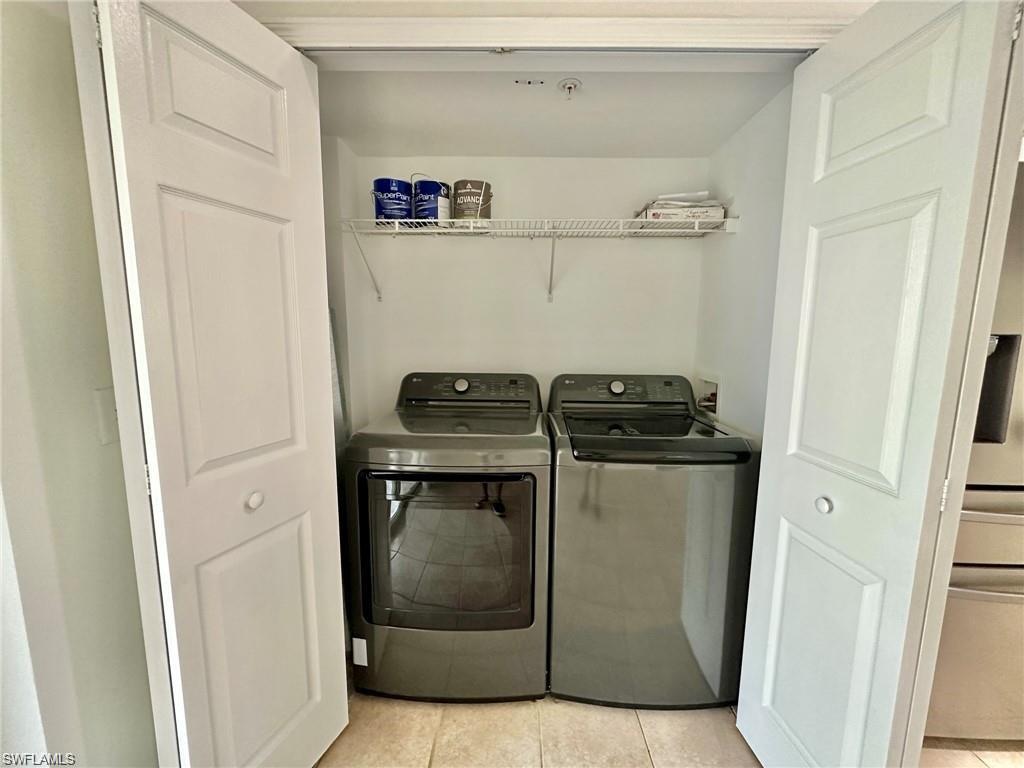 Laundry closet featuring bi-fold doors, a wire shelf, and tile flooring