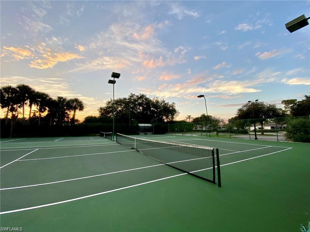 Green hard court tennis facility with multiple courts, permanent nets, and perimeter fencing