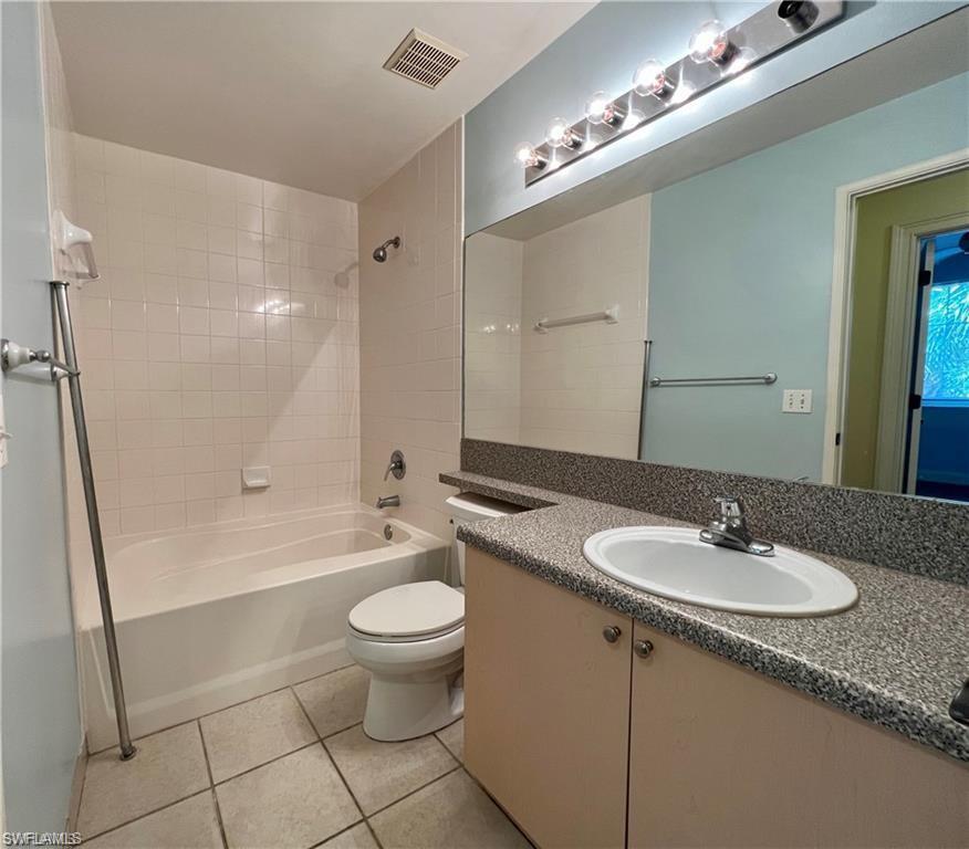 Full bathroom with washtub / shower combination, toilet, vanity, and tile flooring