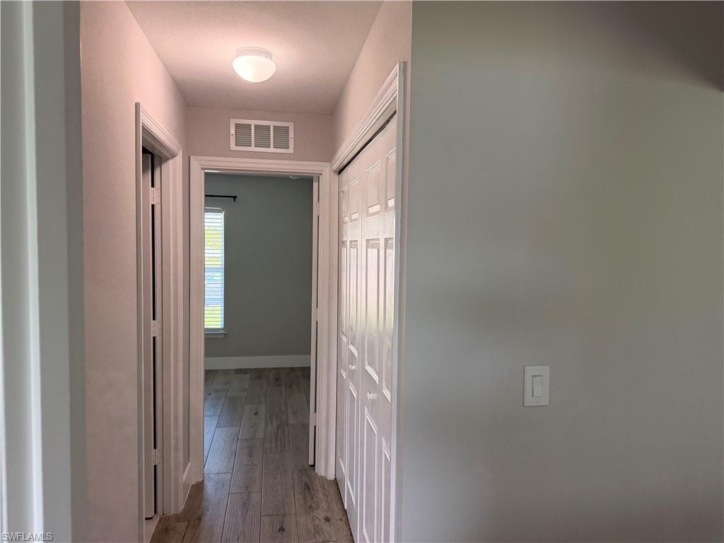 Hallway featuring wood-finish flooring, light gray wall paint, and white trim