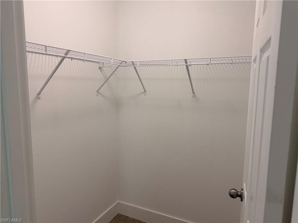 Walk-in closet featuring white wire shelving, light-toned walls, and wood-finish flooring