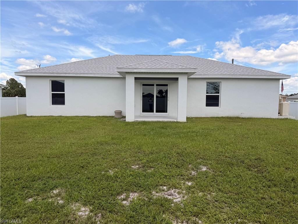 White stucco exterior featuring a grey shingle roof, dual pane windows, and a covered patio with sliding glass doors