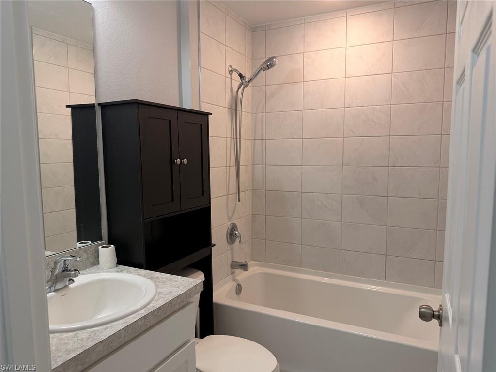 Bathroom featuring a white bathtub, ceramic tile surround, built-in vanity with an integrated sink, and a chrome faucet