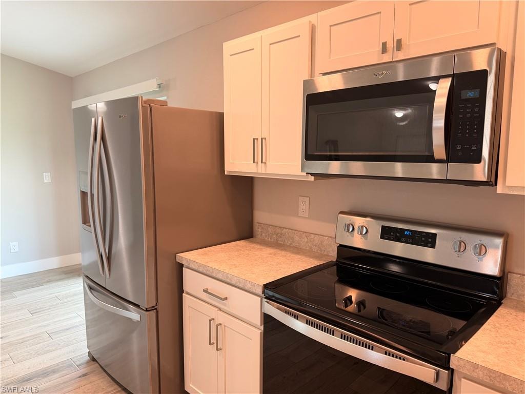 Kitchen featuring stainless steel appliances, white shaker-style cabinetry, and a textured countertop