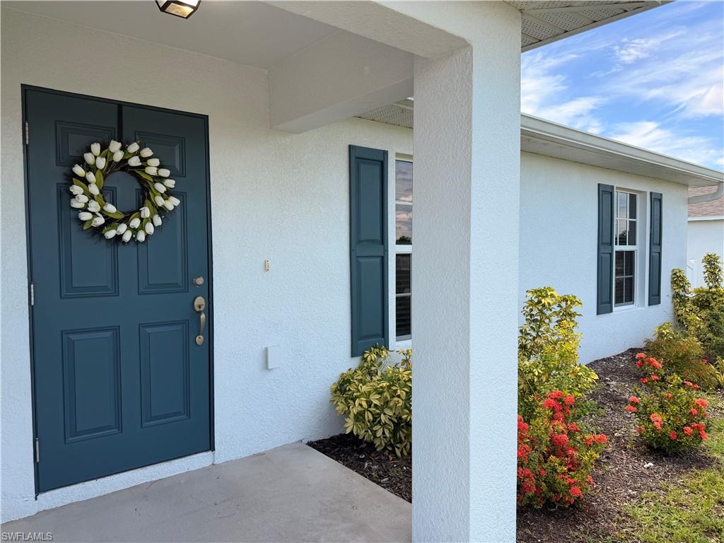 Exterior featuring a paneled entry door, stucco siding, and decorative window shutters