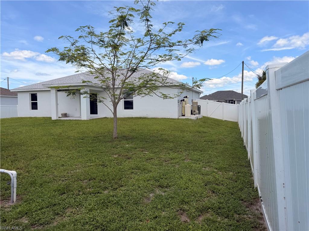 Spacious backyard featuring a privacy fence, a new construction home with a covered patio, and a well-maintained lawn