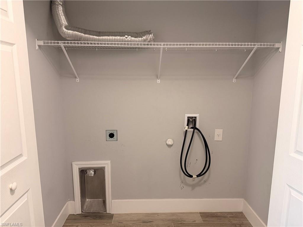 Laundry area featuring wood-finish flooring, white baseboards, and light gray walls