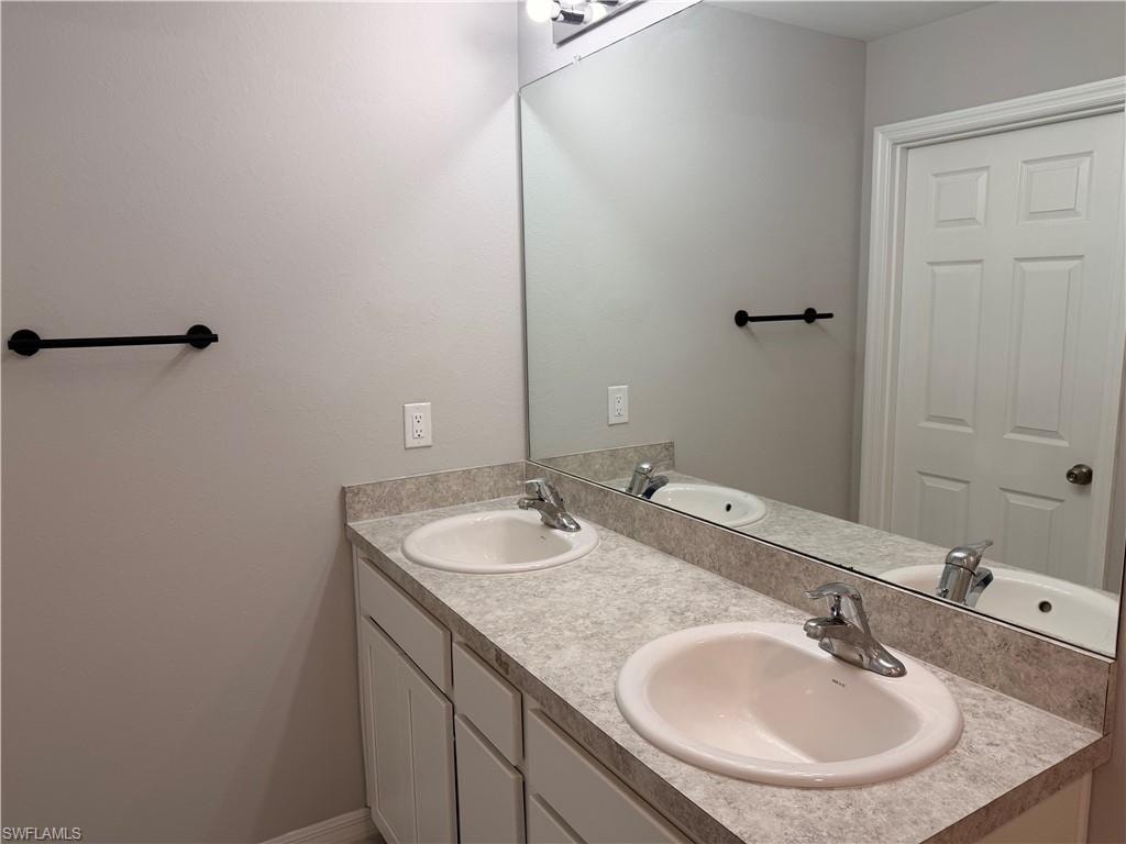 Dual vanity with white ceramic sinks, chrome fixtures, and a speckled countertop