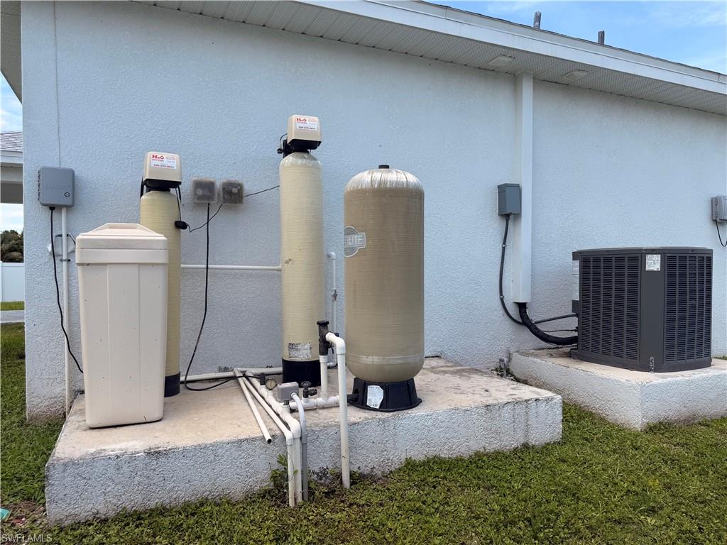 Exterior utility area featuring a water filtration system, water softener, pressure tank, and an air conditioning condenser unit