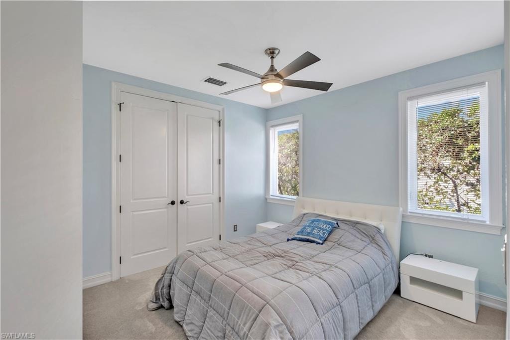 Bedroom with light blue walls, two windows with blinds, and white trim