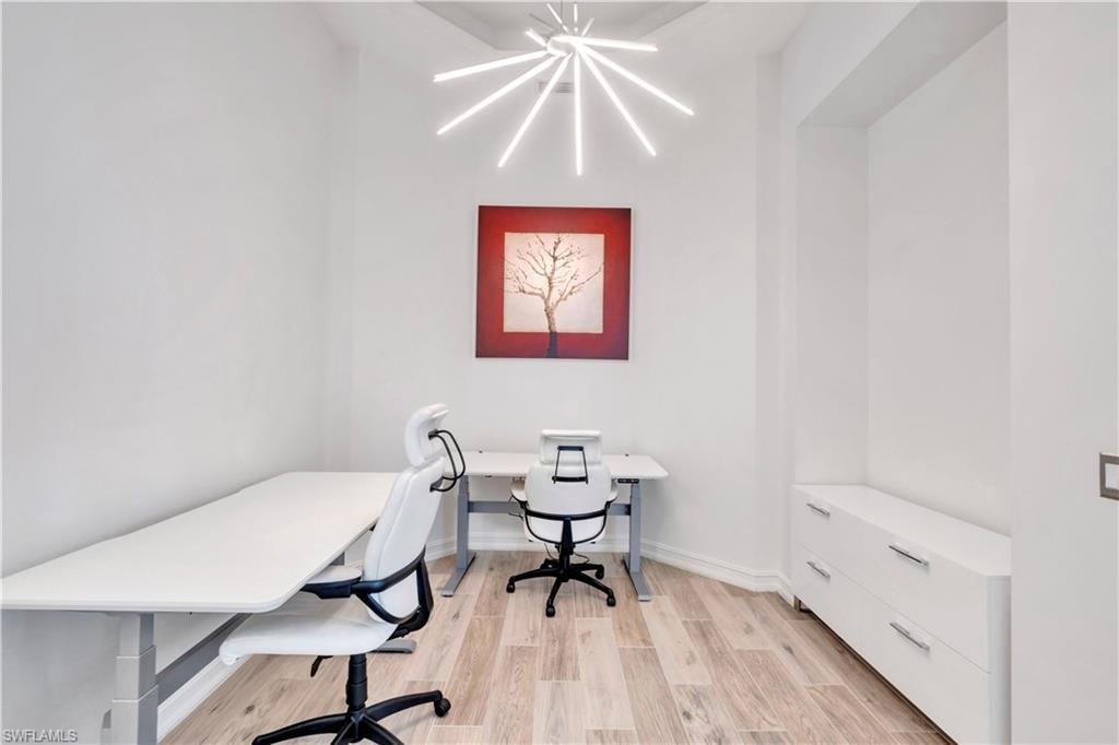 Bright interior space featuring wood-finish flooring, a contemporary ceiling light fixture, and built-in white cabinetry with chrome hardware