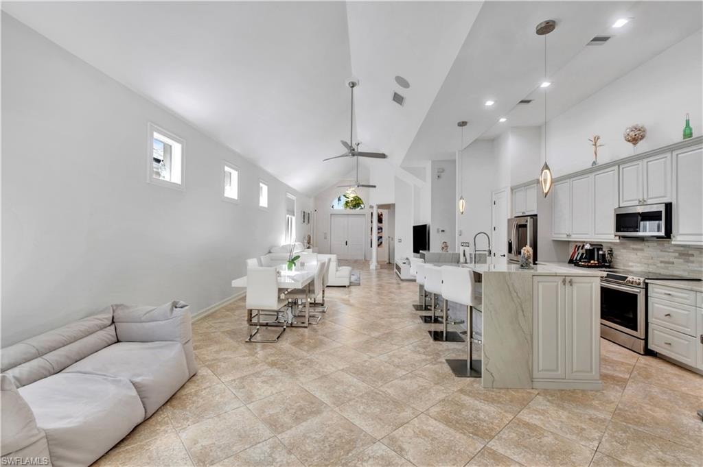 Open-concept living area featuring vaulted ceilings, recessed lighting, and tile flooring