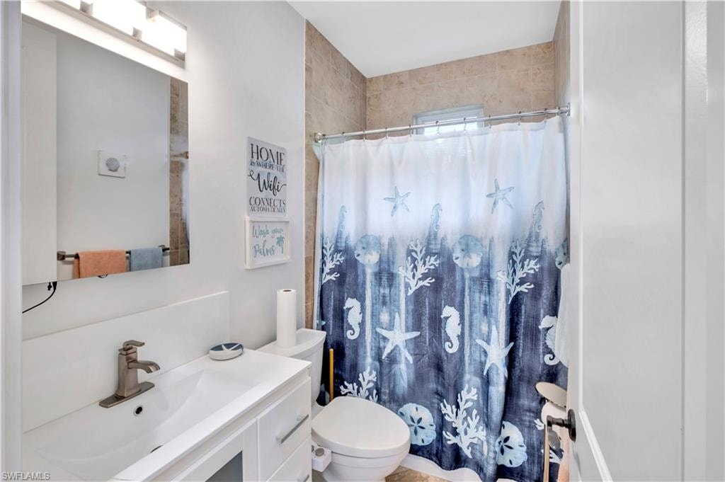 Bathroom featuring a white vanity with an integrated sink, brushed nickel faucet, and a wall-mounted mirror with overhead lighting