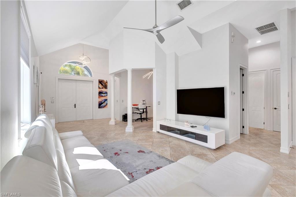 Vaulted ceilings with a ceiling fan, arched transom window above double entry doors, recessed lighting, and tile flooring