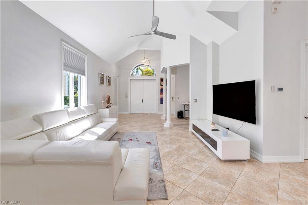 Open-concept living space featuring vaulted ceilings, neutral-toned tile flooring, and a contemporary ceiling fan