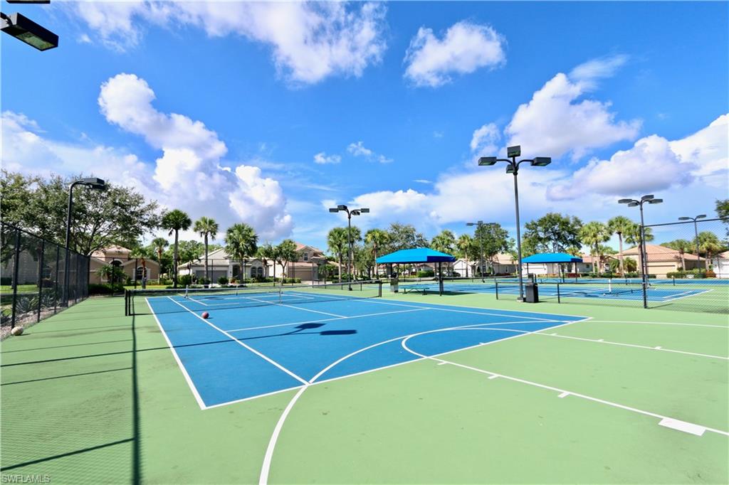 Multiple hard tennis courts featuring blue and green playing surfaces, white court lines, and perimeter fencing