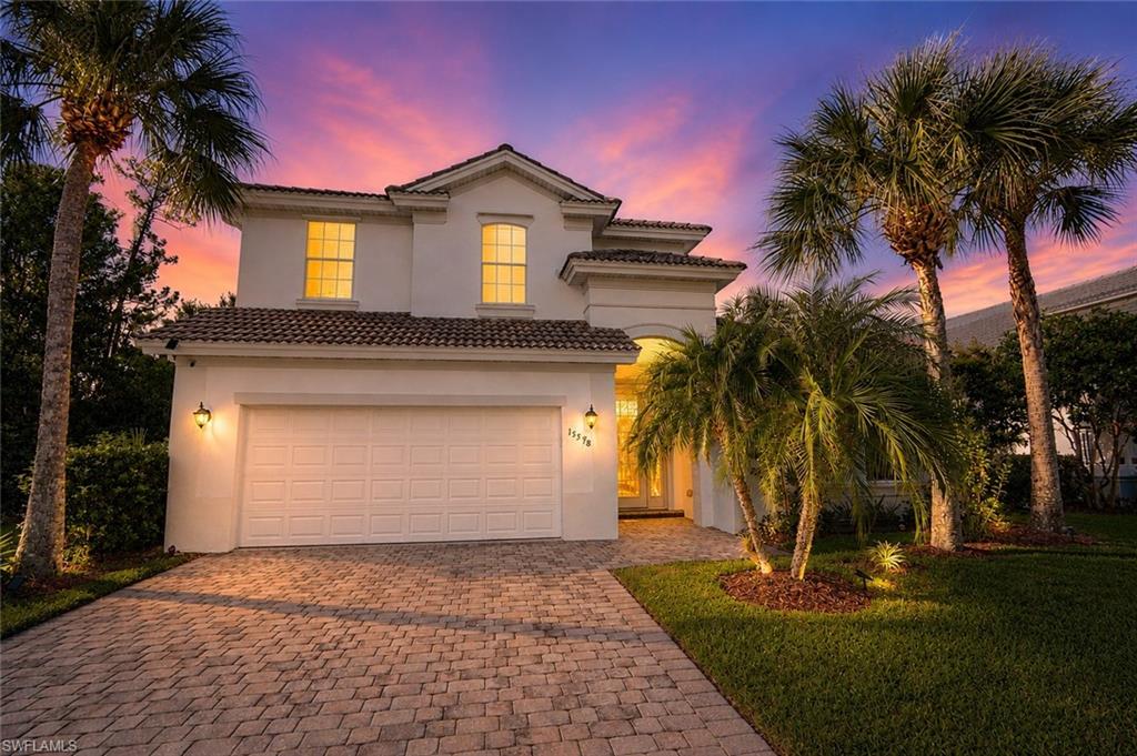Two-story stucco home featuring a tile roof and attached garage