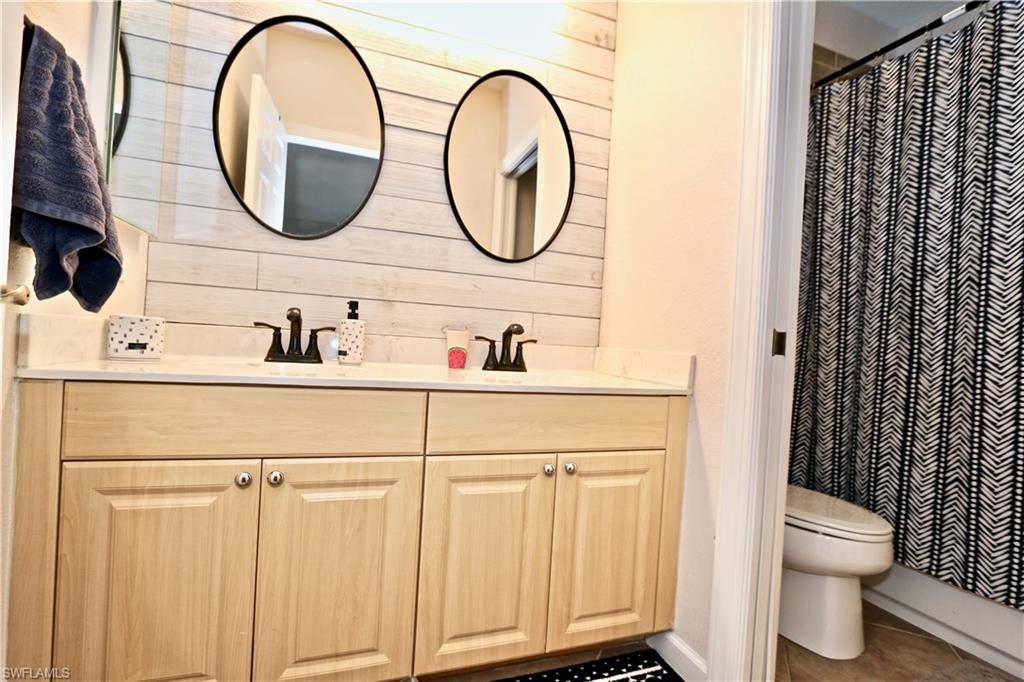 Double vanity with light wood-finish cabinetry and quartz-finish countertop