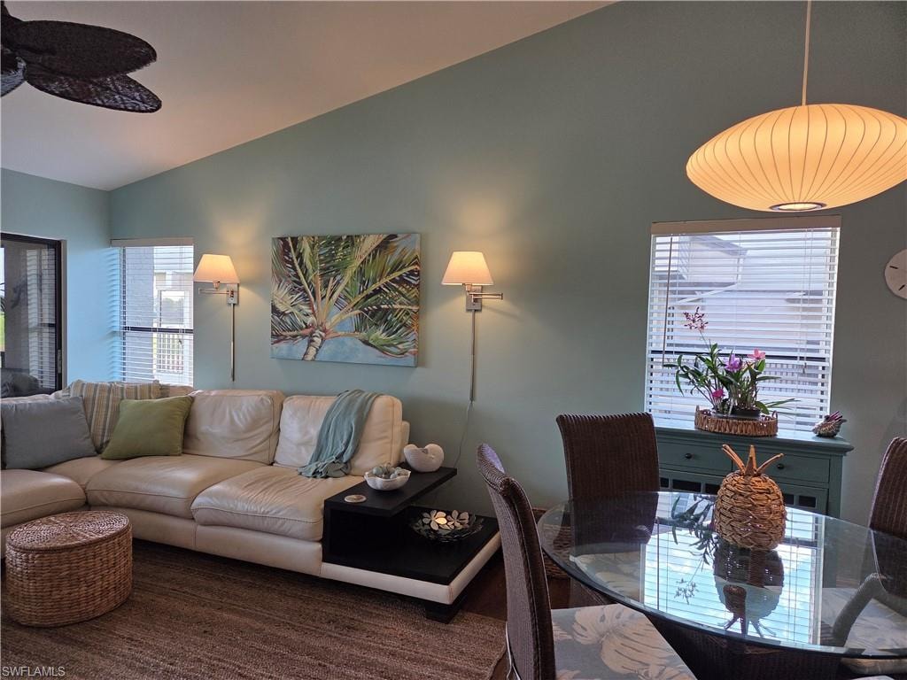 Living area featuring a vaulted ceiling and wall-mounted sconces