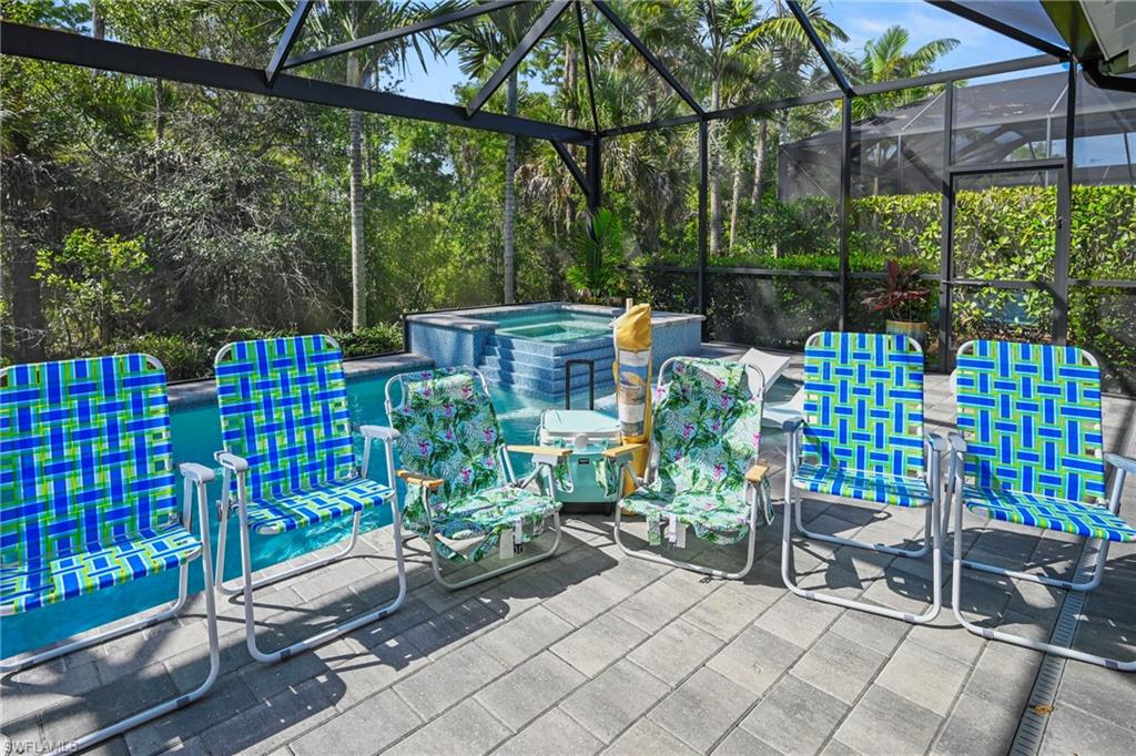 Screened patio featuring a paver deck, a rectangular pool, and an elevated spa with tiled steps