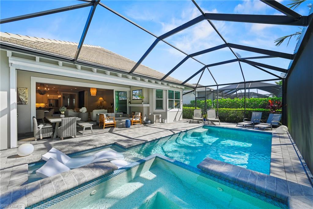 Screened outdoor living area featuring a rectangular pool with integrated spa