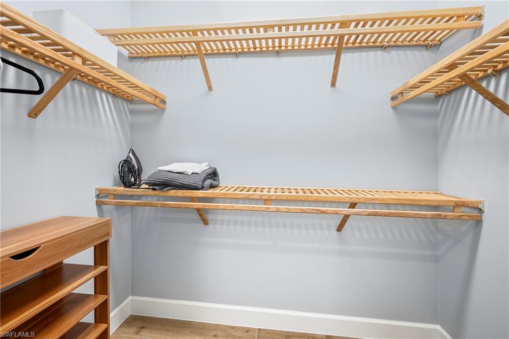 Custom closet system featuring natural wood-finish shelving and wall-mounted hanging rods