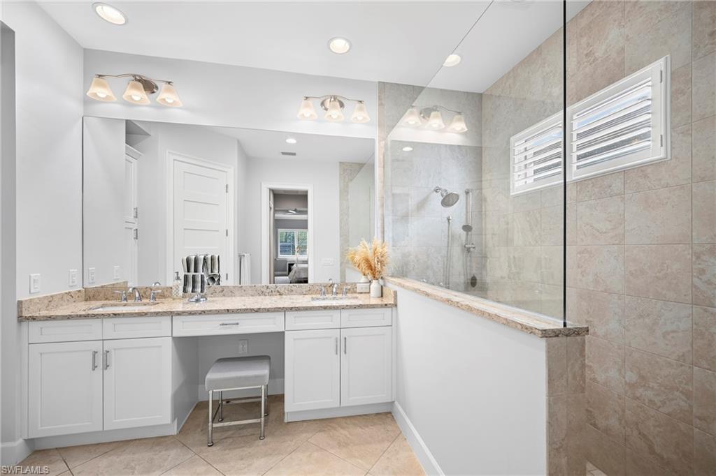 Spacious bathroom featuring a dual vanity with granite countertops, white cabinetry, and a dedicated makeup area