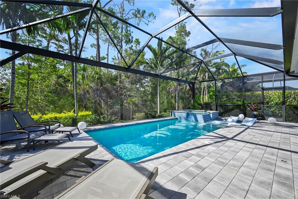 Screened outdoor living area featuring a rectangular pool and integrated spa