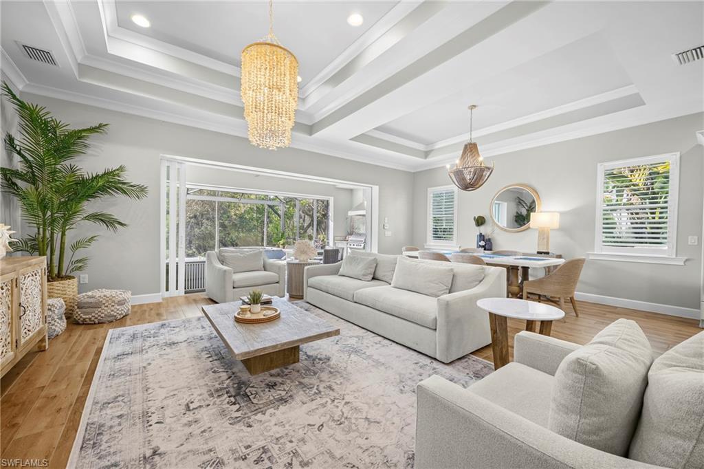 Spacious living area featuring a tray ceiling with recessed lighting and a large decorative chandelier