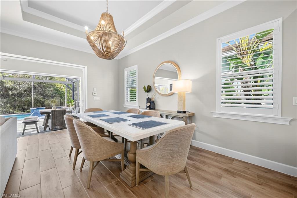 Dining area with wood-finish flooring, coffered ceiling, and a large chandelier