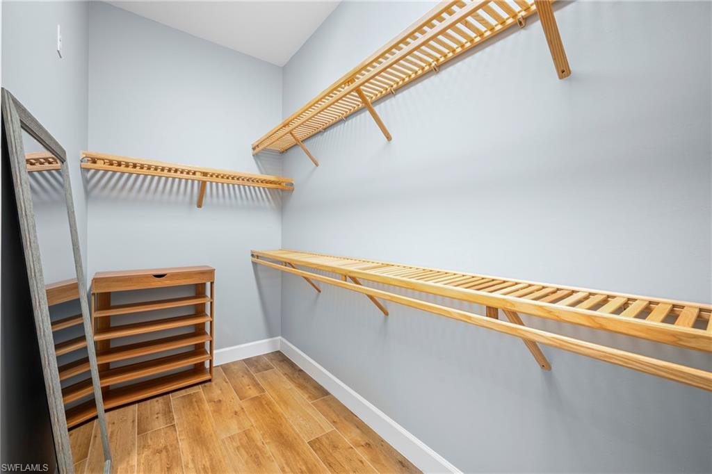 Spacious walk-in closet featuring light wood-finish shelving, clothes rods, and wood-finish flooring