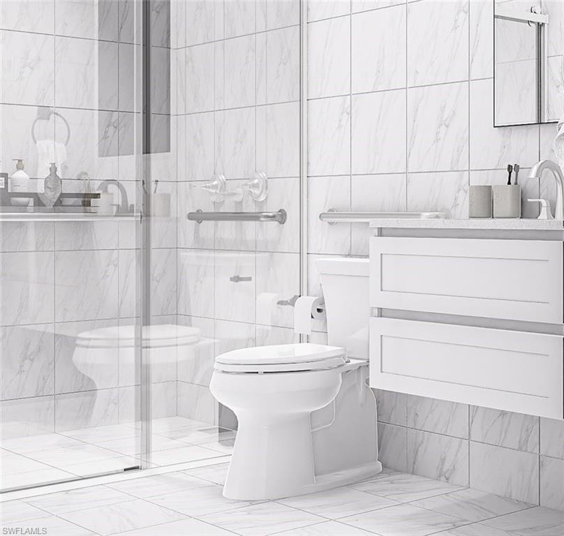 Bathroom with tile walls, vanity, a shower stall, and light marble finish floors