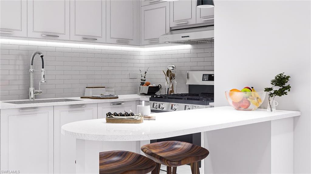 Kitchen with a kitchen breakfast bar, tasteful backsplash, a peninsula, under cabinet range hood, and light stone countertops