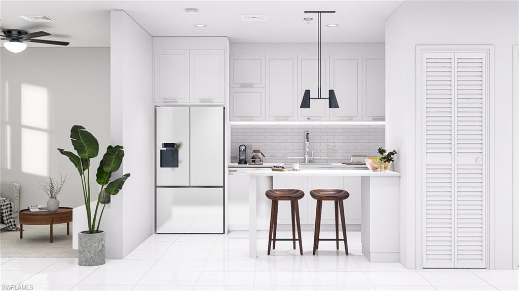 Kitchen with fridge, a kitchen bar, white cabinets, tasteful backsplash, and recessed lighting