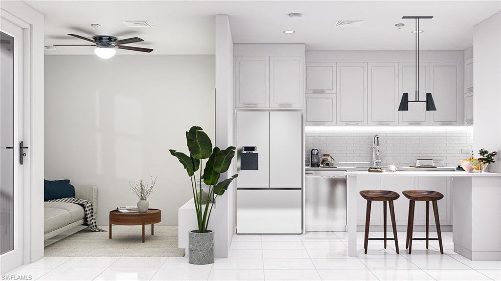 Kitchen with a kitchen breakfast bar, fridge with ice dispenser, white cabinets, hanging light fixtures, and tasteful backsplash