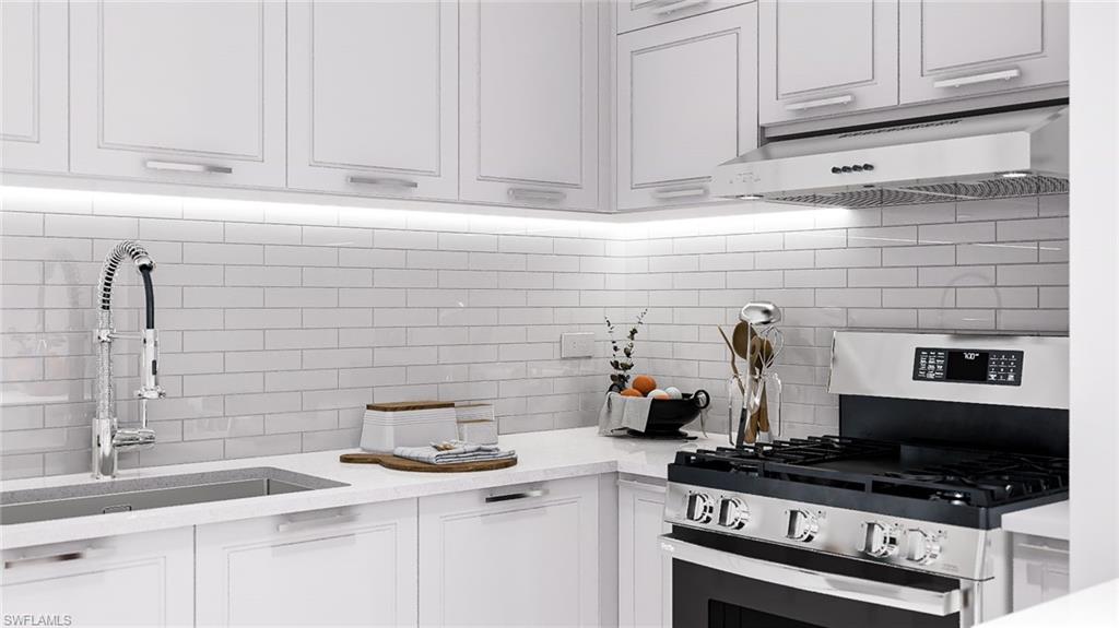 Kitchen with stainless steel gas stove, decorative backsplash, under cabinet range hood, white cabinets, and light stone countertops