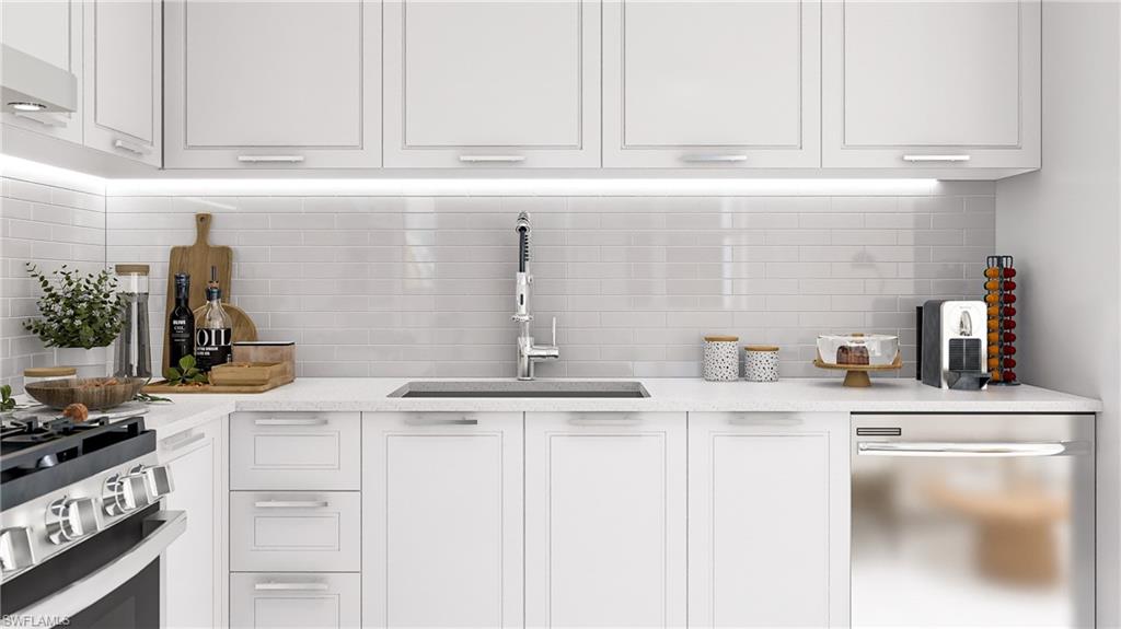 Kitchen with white cabinets, stainless steel appliances, backsplash, and light stone countertops