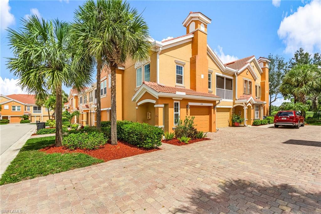 Mediterranean / spanish home with decorative driveway, a tiled roof, stucco siding, an attached garage, and a chimney