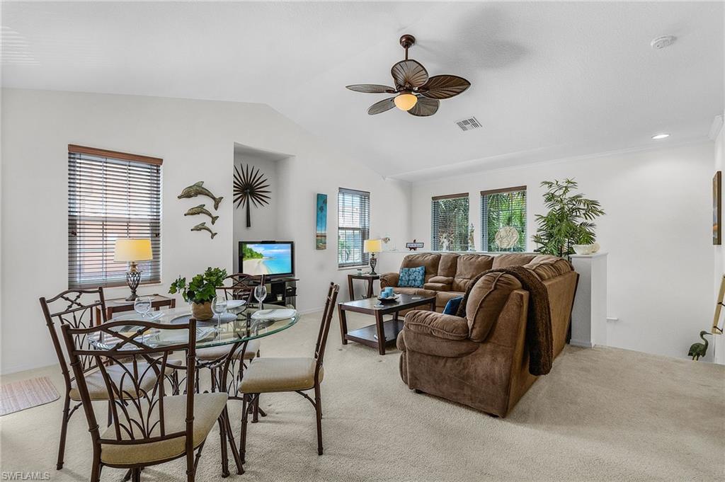 Living room with a ceiling fan, light carpet, and vaulted ceiling