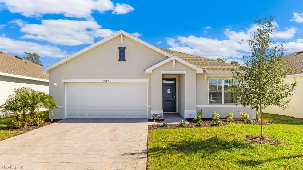 Model Home - Contemporary single-story residence featuring a neutral stucco exterior, an attached two-car garage with a paver driveway, and a welcoming dark entry door