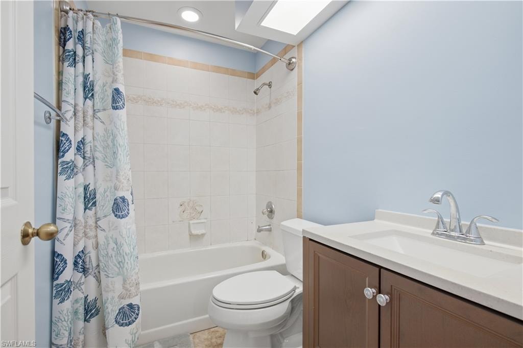 Bathroom featuring a white tub, tiled shower surround, recessed lighting, and a vanity with an integrated sink and wood-finish cabinetry