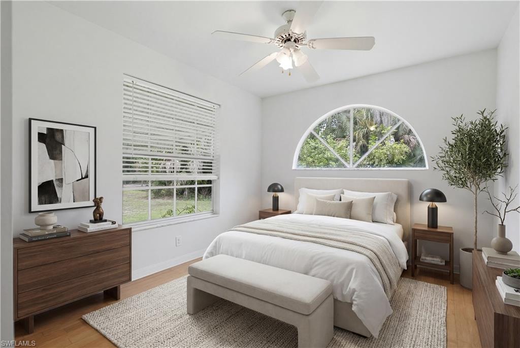 Bright interior space featuring a half-round architectural window, a rectangular window with horizontal blinds, a ceiling fan, light wood-finish flooring, and white painted walls