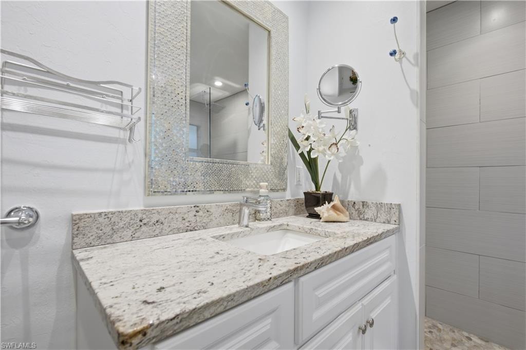 Bathroom vanity featuring a speckled countertop, integrated sink, and white cabinetry