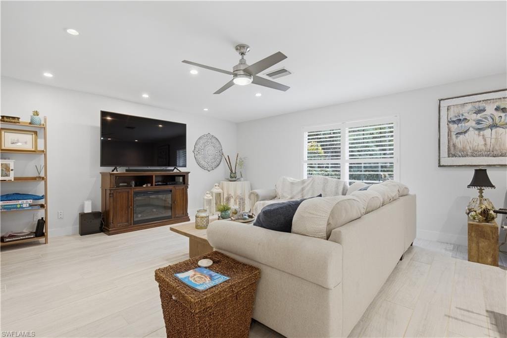 Spacious living area featuring light wood-finish flooring, recessed lighting, and a contemporary ceiling fan
