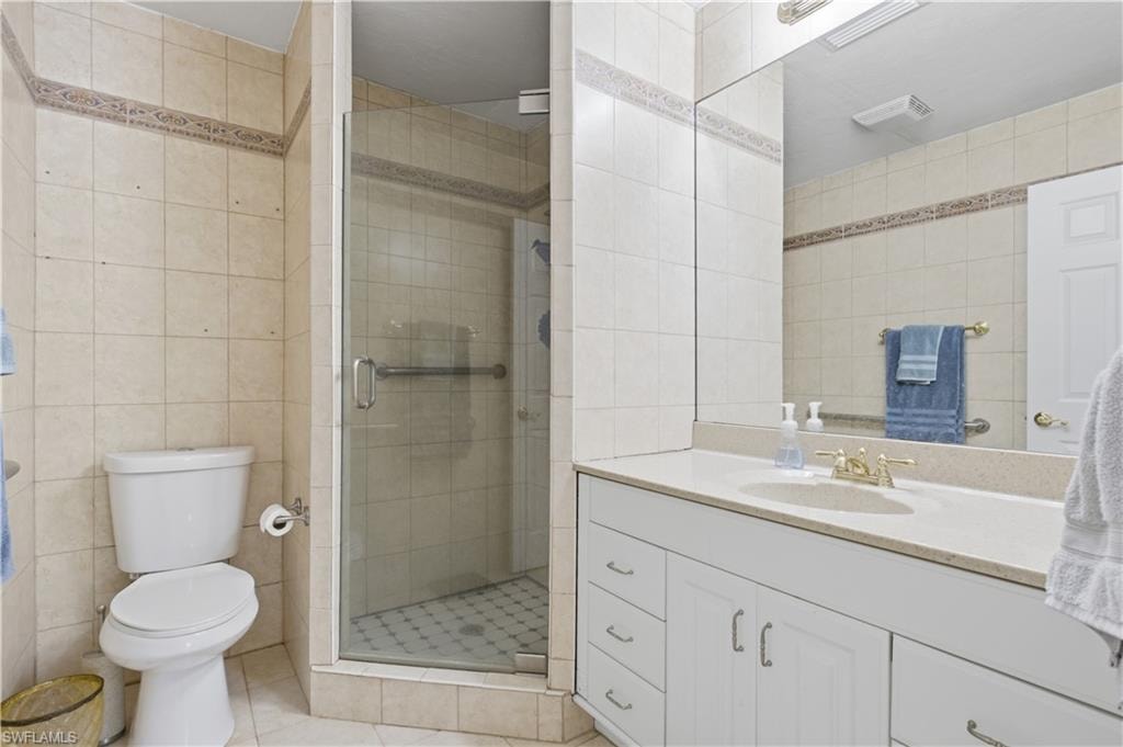 Bathroom featuring a glass-enclosed shower, white vanity with integrated sink, light-toned countertop, and full-width wall mirror