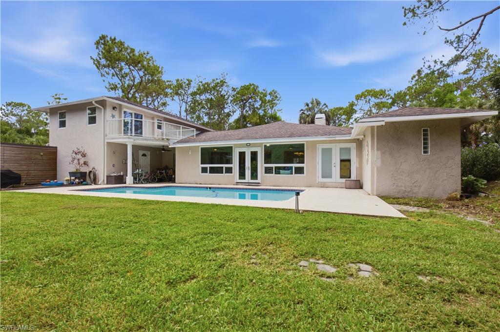 Expansive backyard featuring a rectangular swimming pool with integrated concrete patio